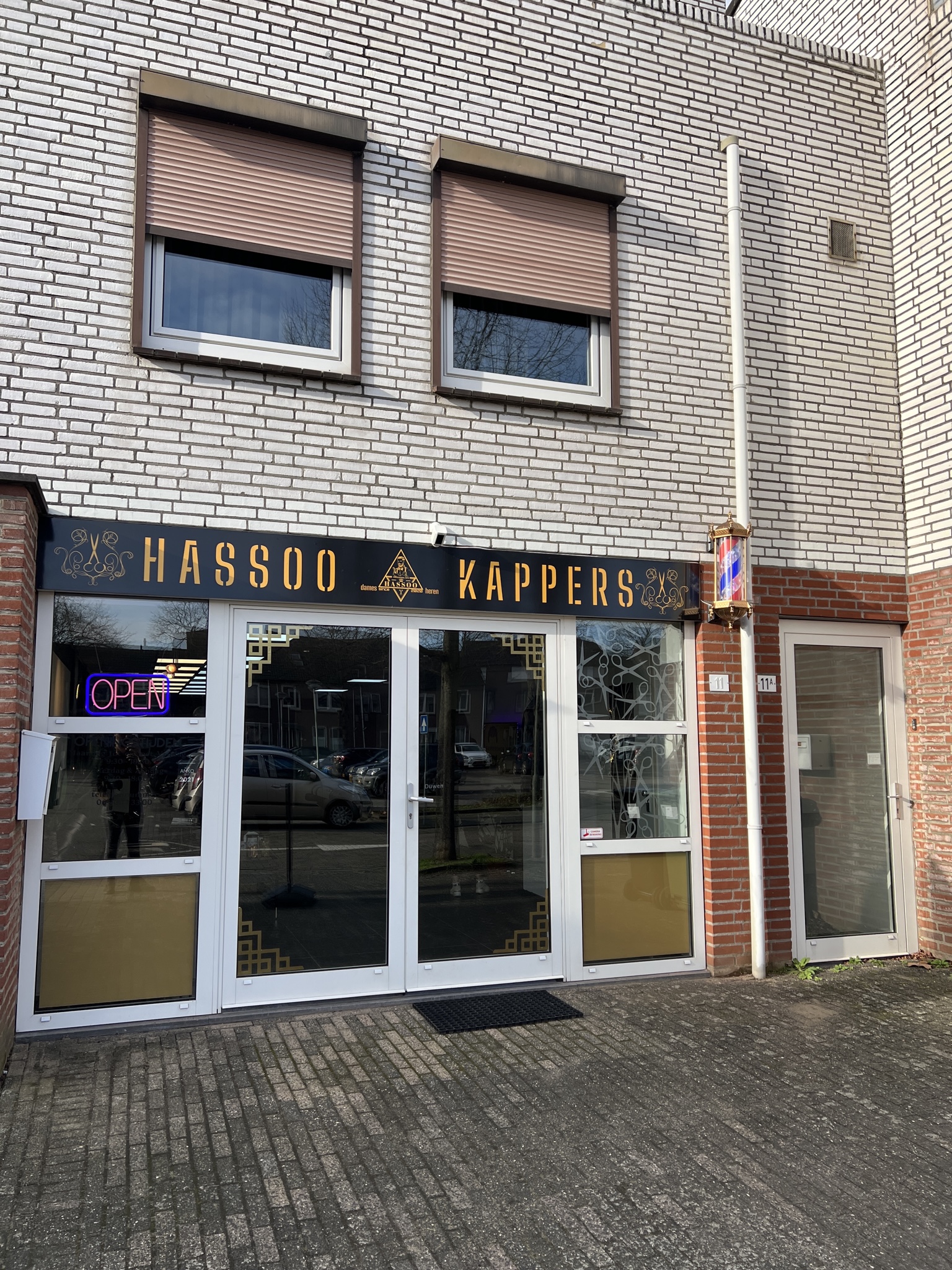 De gevel van Hassoo Kappers aan de Raadhuisstraat, met het gouden bord en de barberspaal
